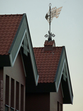 Close up photo image of weather vane and two dormers of house in fishing village.